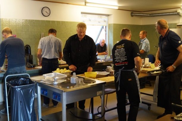 Gourmetgris p&#229; gaflen. M&#230;ndene arbejder h&#229;rdt med maden, og f&#229;r sig et iskoldt glas vand. Foto: Allan Lodberg